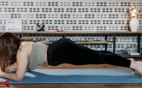 A woman doing plank exercise indoors on a blue mat, promoting fitness and healthy lifestyle.